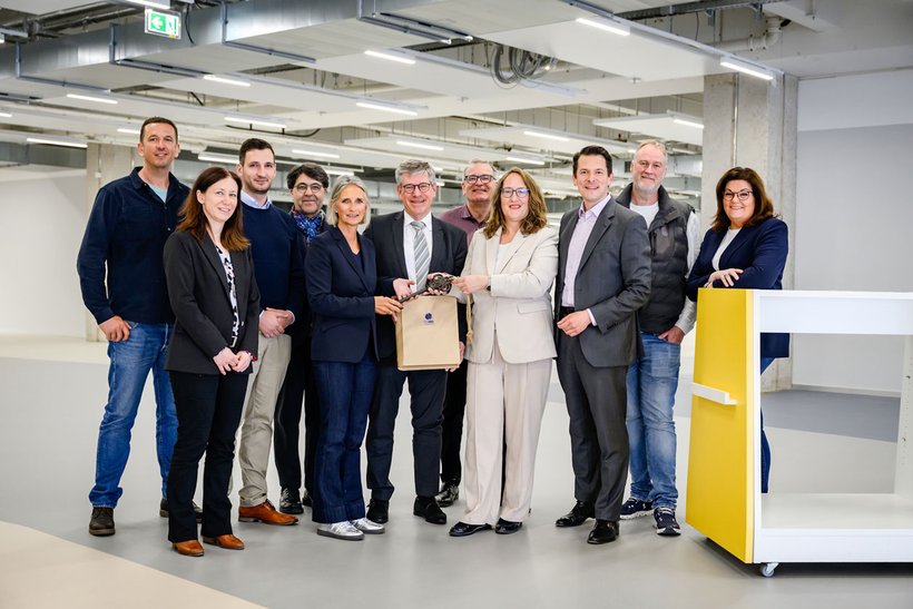 Das Foto zeigt die noch leeren Räume und die Personen während der Schlüsselübergabe